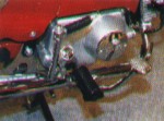 Páka mechanického spouštěče, stupačka a pedál zadní brzdy na pravé straně.